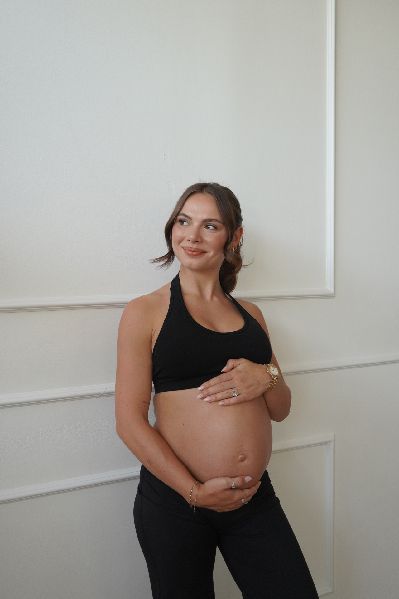 Georgia standing and smiling while cradling her bump